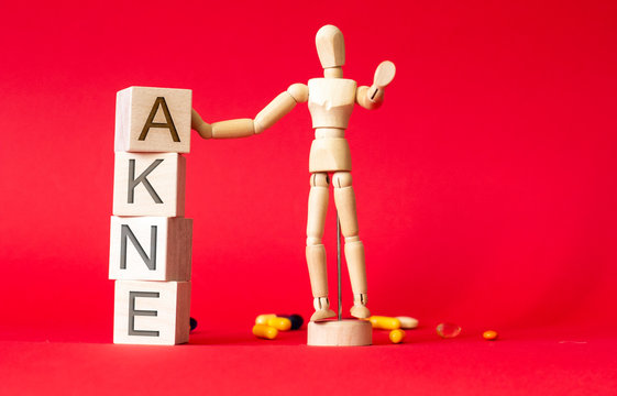 Acne on wooden cubes and wooden man on a red background