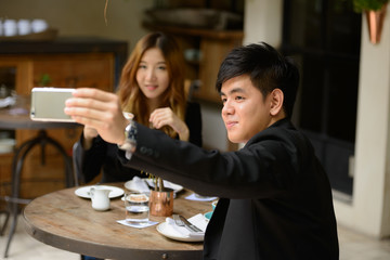 Young Asian business couple taking selfie together at the coffee shop