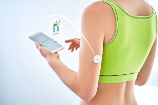 Diabetic patient checking glucose level with a remote sensor and mobile phone. Online monitoring glucose levels without blood using digital glucose meter. Technology in diabetes treatment