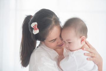 happy loving family. mother playing with her baby in the bedroom. asian mother hugging and holding her baby. family, motherhood, parenting, family and child care concept. White background.