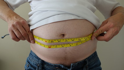 Front Of Overweight Man Wearing Blue Jeans And White Tshirt Showing Belly Fat With Tape Measure 004