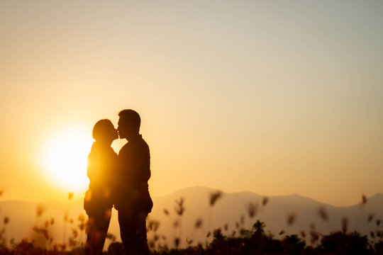 The shadow of a backlit couple who is kissing happily at sunset