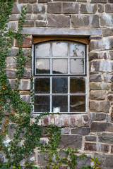 old window in a stone wall with ivy
