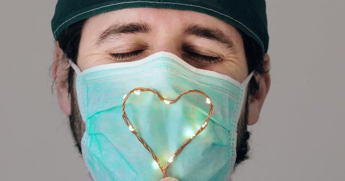 Medico felice sorride con il simbolo del cuore davanti la mascherina chirurgica per donare speranza ai malati di covid-19. Coronavirus.
