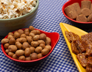 several bowls with  peanuts  and popcorn on the  table