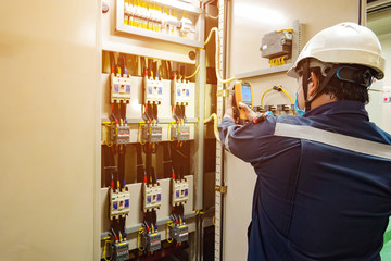 Electrician inspects the power control to find the abnormal condition of transformer by using thermo scanner.  - obrazy, fototapety, plakaty