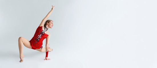 Rhythmic gymnastics. Beautiful sportswoman in performance costume dancing on white background, copy...