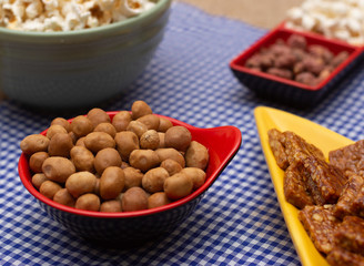 several bowls with  peanuts  and popcorn on the  table