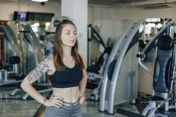 Obraz premium Attractive athletic girl stands on the background of simulators in the gym. healthy lifestyle.