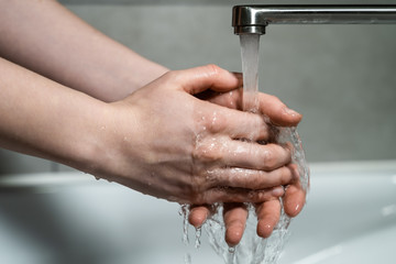 Man washing soapy hands in bathroom