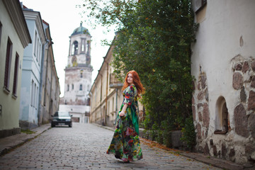 Fototapeta na wymiar beautiful red-haired girl walks along the old streets of Vyborg