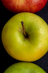 Three apples, one green and two red and yellow on a dark background