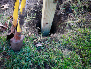 Building new privacy fence in progress: wooden post in hole ready for concrete foundation