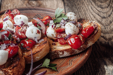 Tomato bruschetta with mozzarella in rural ceramic bowl