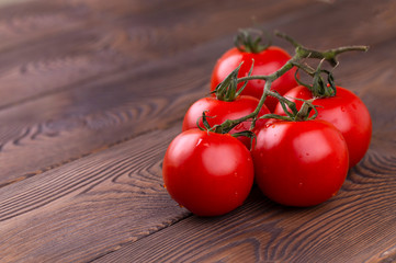 Branch of red organic tomatoes on a wooden table in rustic style. Harvesting tomatoes.
