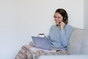 Female working remotely at home with laptop and headphones