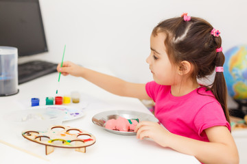 Little girl painting in her nursery at home