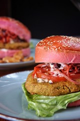 Closeup of two vegeburgers on light blue plate and wooden table. Vertical, shallow DOF.