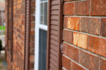 red brick wall outside with window and shutters