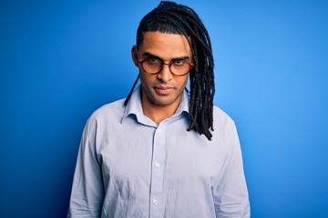 Young handsome african american man with dreadlocks wearing casual shirt and glasses skeptic and nervous, frowning upset because of problem. Negative person.