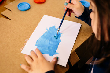 Child painting at home with paints and brush. School activity