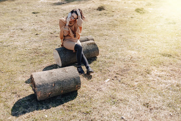 young attractive stylish girl on nature on forest background with phone on a sunny day. outdoor holidays and dependence on technology.