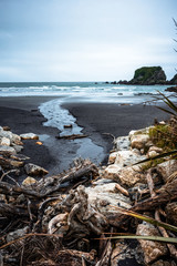 Beautiful image of a beach at low tide with wet rocks in the foreground taken on a cloudy winter day in Cape Fouldwind, New Zealand