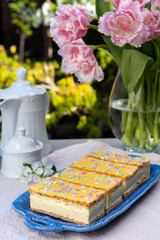 Tompouce cakes with whipped cream and yellow icing served in sunny spring garden