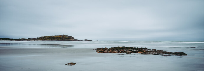 Beautiful panoramic photo of a beach at low tide taken on a cloudy winter day in Cape Fouldwind, New Zealand