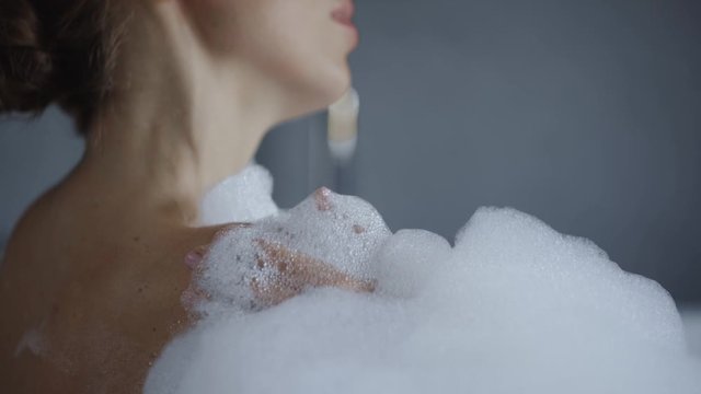 close up view of attractive young woman washing in bubble bath