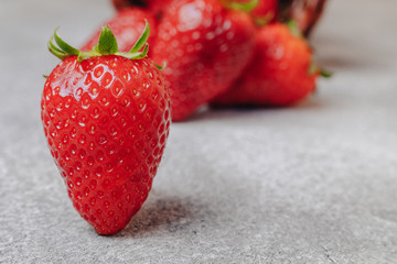 juicy strawberries poured out chaotically on a concrete light background. delicious fruits in summer season. natural products and natural resources.