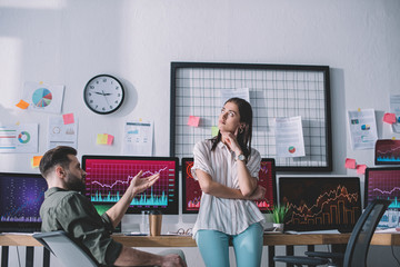 Data analyst looking at pensive colleague near computers in office