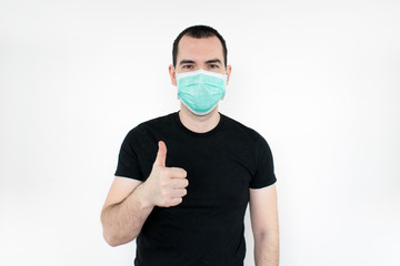 caucasian male man young. standat white background, wear mask on face,   thumbs up gesture one hand,  protect yourself, safe people. Coronavirus.