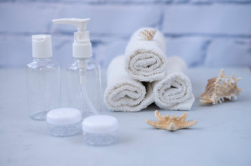 Fototapeta na wymiar Plastic containers. Spa composition, recreation and hospitality. Beauty and skin care concept. Plastic bottles, lens containers and white towels on a light background