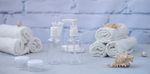 Plastic containers. Spa composition, recreation and hospitality. Beauty and skin care concept.  Plastic bottles, lens containers and white towels on a light background