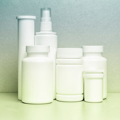 5 white vials without labels for medicines, vitamins, sprays, liquids are on a gray shelf. layout for the design of the pharmacy and the store.