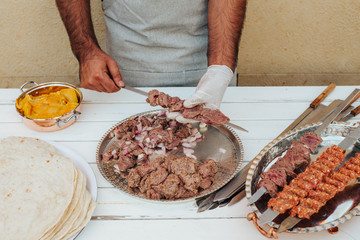Process of making kebab. Meat on skewer. Cooker follow hygiene and use gloves. Mixed grill. Traditional arabic dish. Family dinner. Real photos of cooking