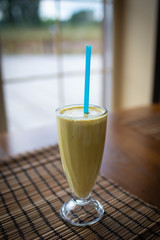 Freshly blended green fruit smoothie in glass jar with straw. Turquoise blue background, copy space