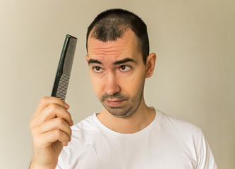 hair loss symptoms and causes, man model black hair young closeup hold hair brush