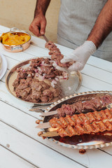 Process of making kebab. Meat on skewer. Cooker follow hygiene and use gloves. Mixed grill. Traditional arabic dish. Family dinner. Real photos of cooking