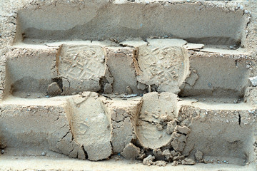 Shoes print the track of bulldozer on the sand.