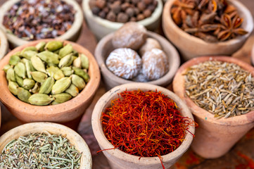 Indian spices collection, dried colorful condiment, nuts, pods and seeds and another spices in clay bowls