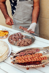 Process of making kebab. Meat on skewer. Cooker follow hygiene and use gloves. Mixed grill. Traditional arabic dish. Family dinner. Real photos of cooking
