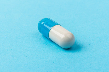 Pills isolated on blue background. Medical drug capsule. Concept of coronavirus