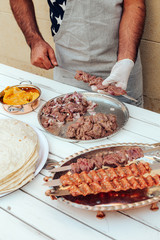 Process of making kebab. Meat on skewer. Cooker follow hygiene and use gloves. Mixed grill. Traditional arabic dish. Family dinner. Real photos of cooking