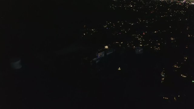 AERIAL: Slow Tilt Move over Hollywood Hills at Night revealing Los Angeles City Lights 