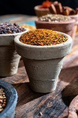 Indian spices collection, dried colorful condiment, nuts, pods and seeds and another spices in clay bowls