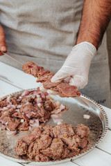 Process of making kebab. Meat on skewer. Cooker follow hygiene and use gloves. Mixed grill. Traditional arabic dish. Family dinner. Real photos of cooking