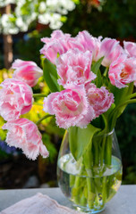 Vase with light pink tulip flowers in spring sunny garden