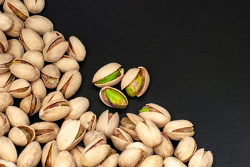 Roasted and fresh pistachios scattered on a black background. View from above. Place for text. Copy space